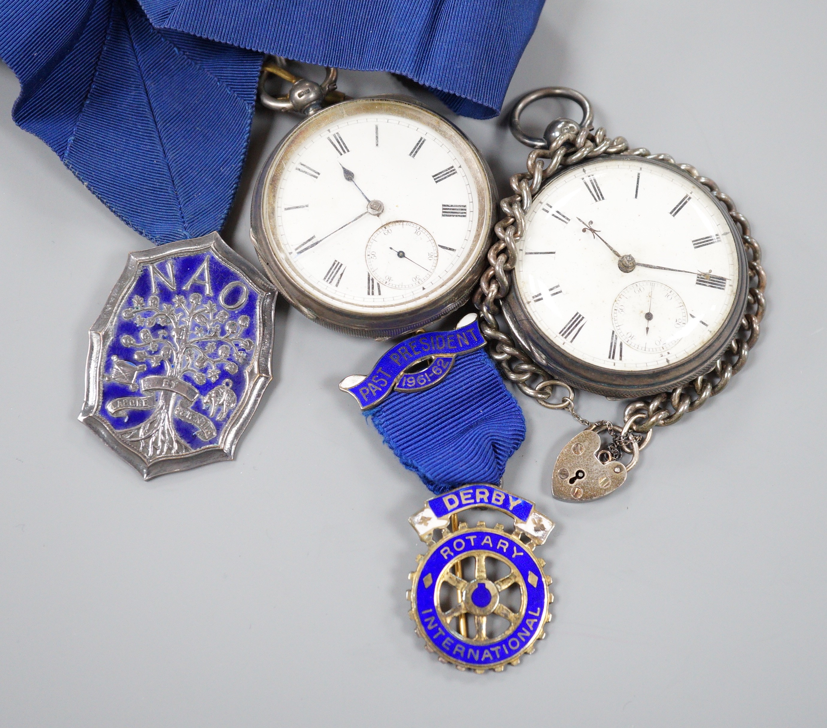 A small collection of silver badges and medals together with two silver pocket watches and a bracelet.